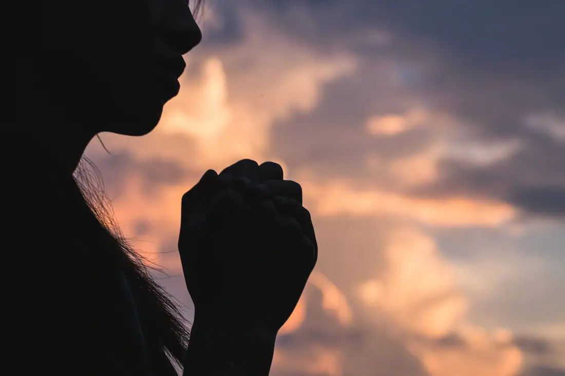 Silent woman praying silhouette during sunset, symbolizing hope, faith, and recovery in addiction treatment.