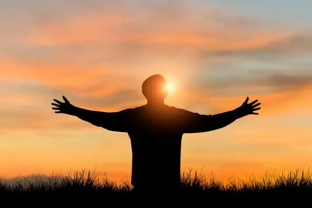 Hopeful person with outstretched arms during sunrise, symbolizing recovery and new beginnings at Firm Foundation Treatment Center.