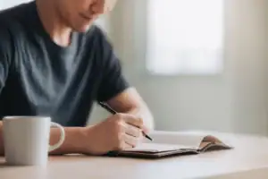 A man writes New Year's resolutions for recovery.