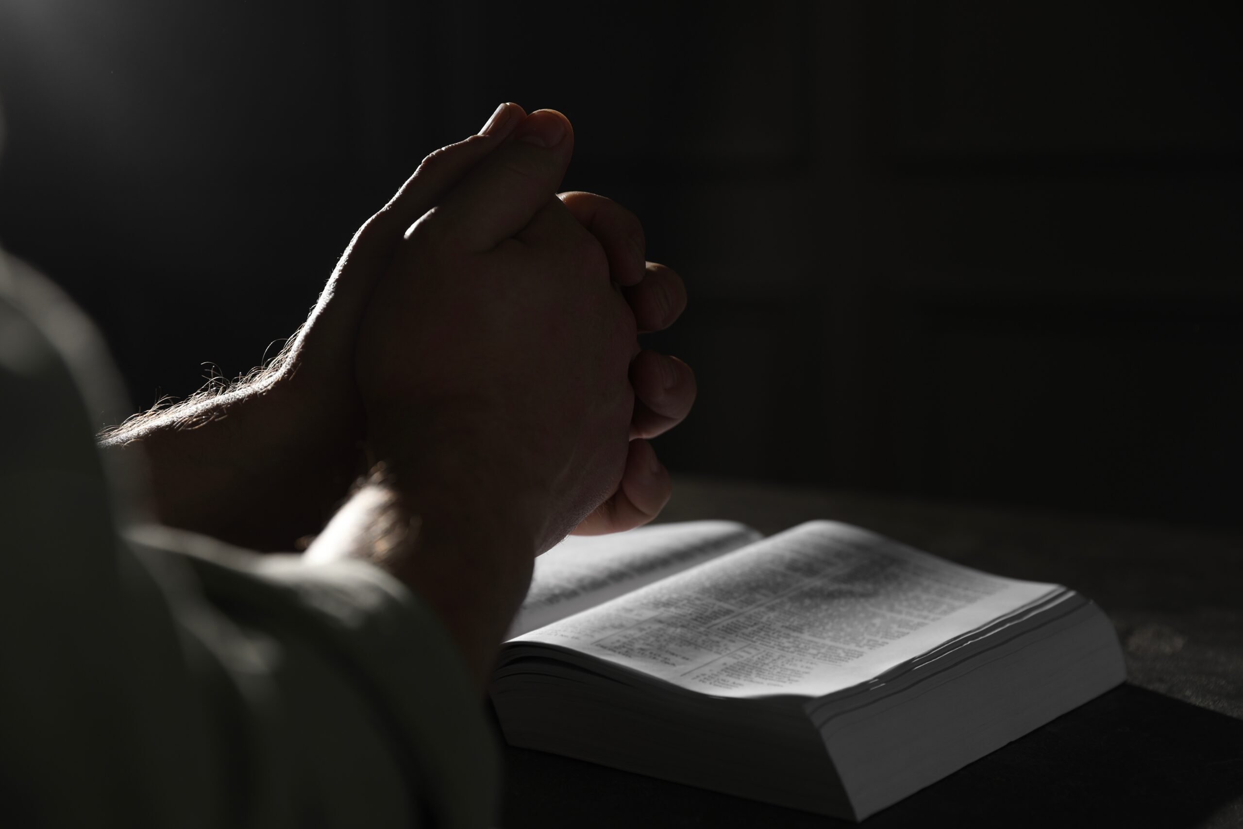 Man praying over Bible about What does faith without works mean.